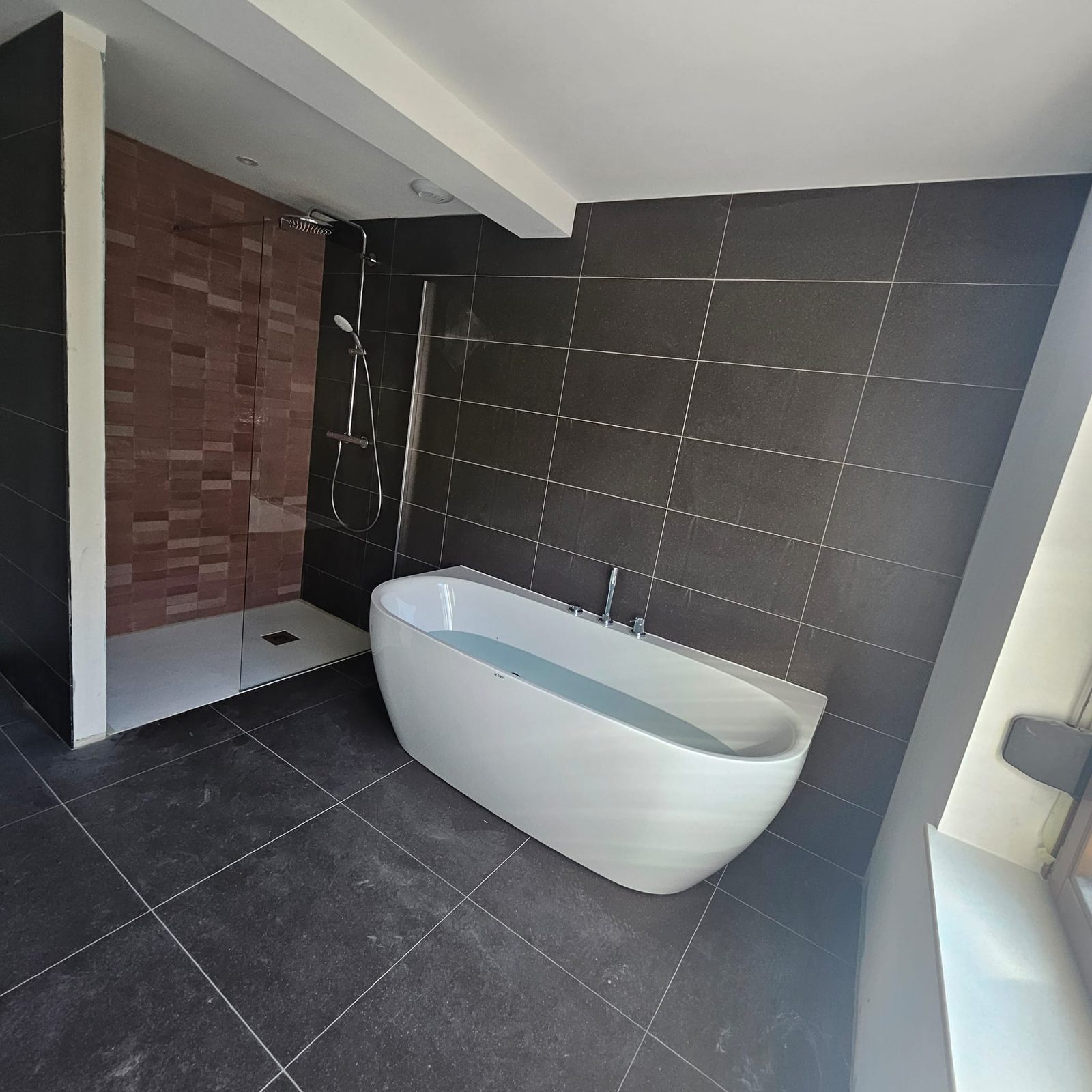 Salle de bain avec baignoire îlot et carrelage anthracite